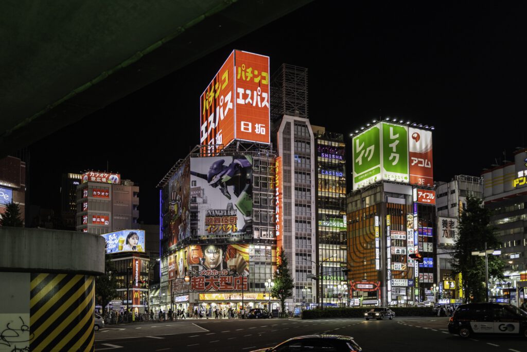 Night view of Kabukicho in Shinjuku, Tokyo, with bright neon signs and bustling streets.