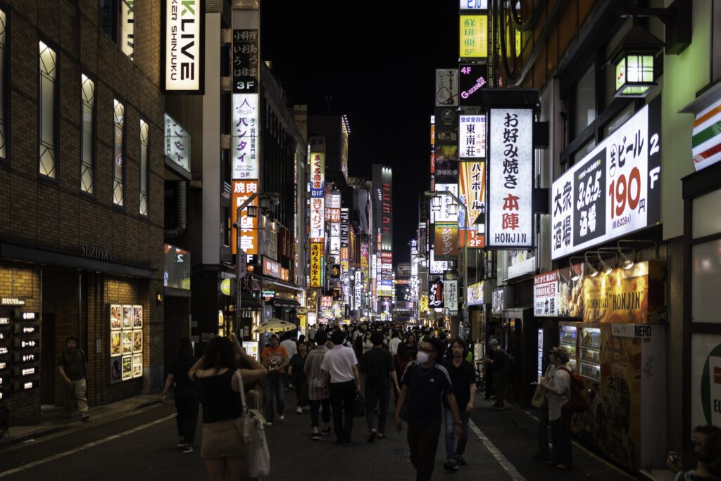 Night view of Kabukicho in Shinjuku, Tokyo, with illuminated signs and a busy street.