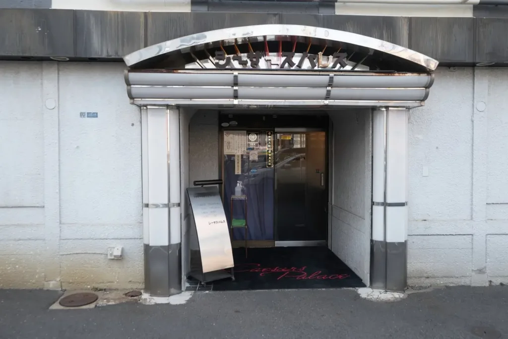 Entrance to a modern Japanese venue on a city tour stop; grey facade with reflective signage.